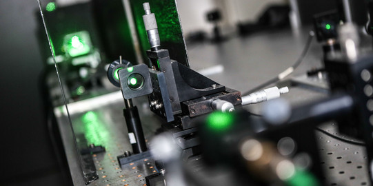 Eine Detailaufnahme eines Lasers im Labor in grünen Farben.